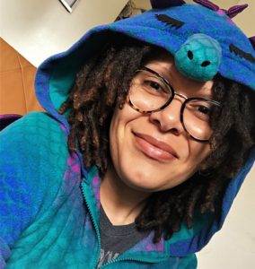 person with locks and light skin in blue and purple dragon pajamas